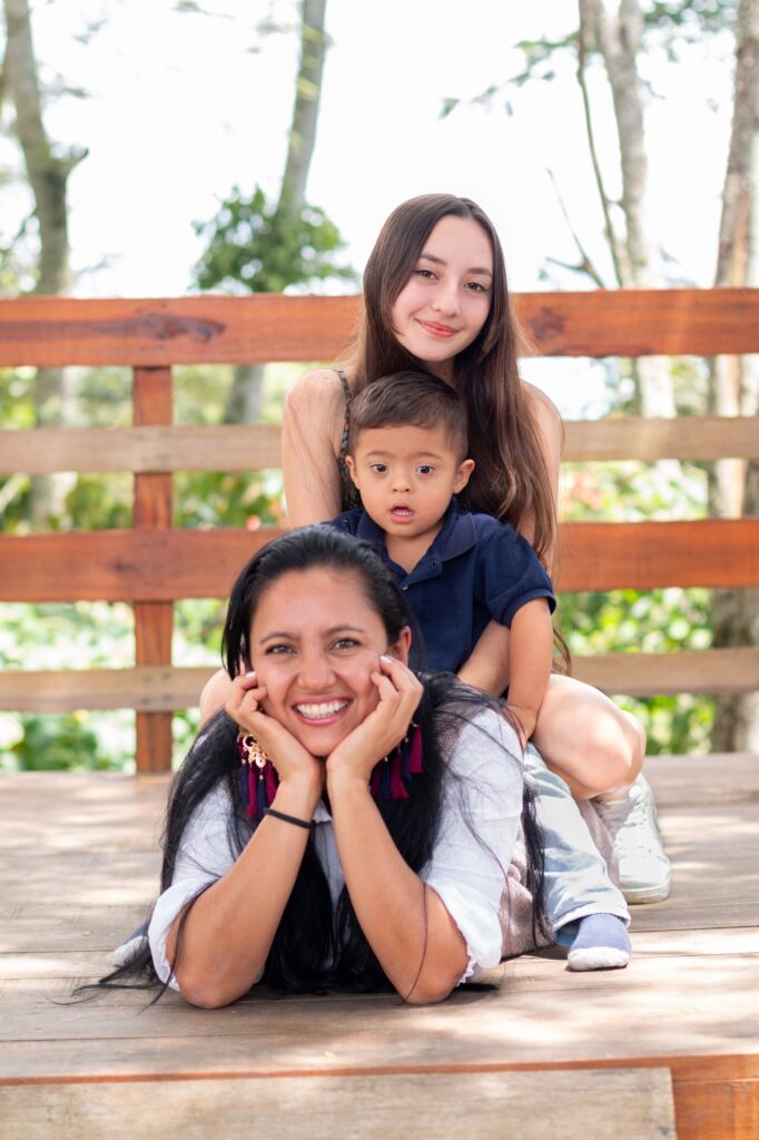 Boy with his sister on his mother's back smiling and looking at the camera. Colombian family.